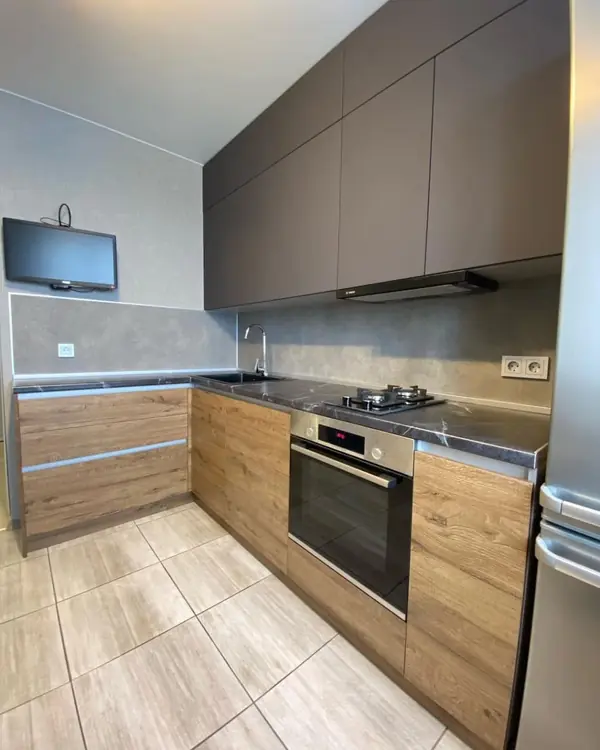 Угловая кухня в коричневом цвете с матовыми и древесными фасадами