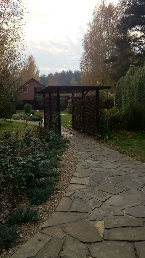 Центральная дорожка из натурального камня, ведущая через деревянную перголу