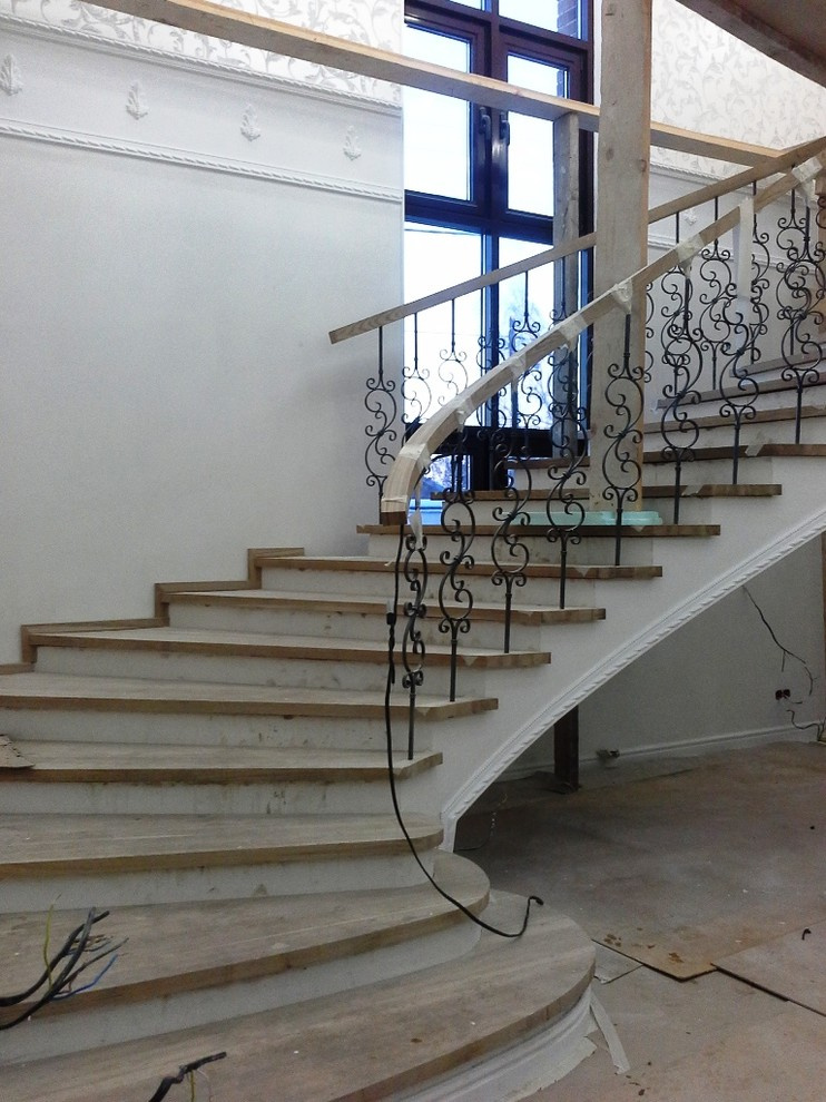 Бетонная лестница со ступенями из дуба и кованными балясинаями