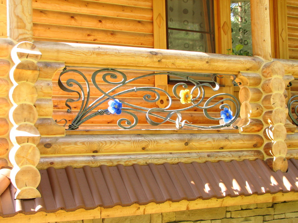 Кованое ограждение балкона в деревянном доме с витражными цветами