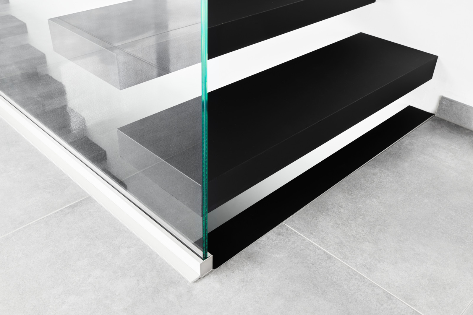 Консольная лестница в черном матовом цвете с ограждением из белого стекла