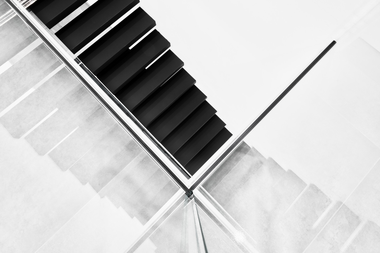 Консольная лестница в черном матовом цвете с ограждением из белого стекла