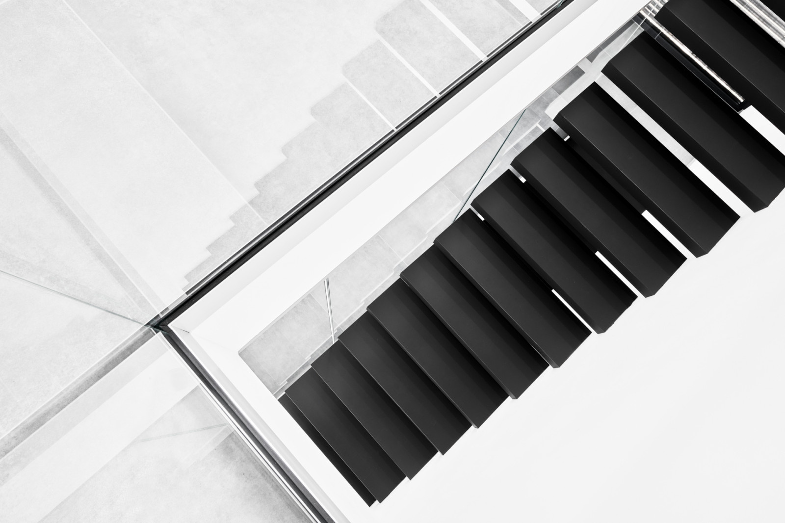 Консольная лестница в черном матовом цвете с ограждением из белого стекла