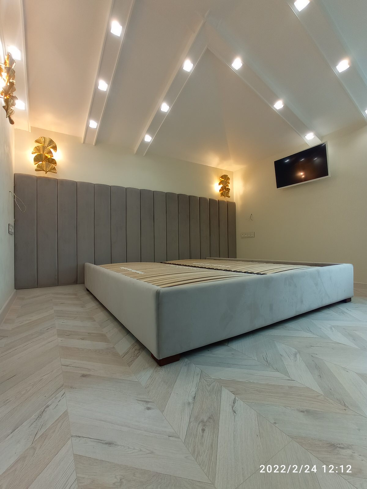 Серая кровать с панелями и золотыми бра