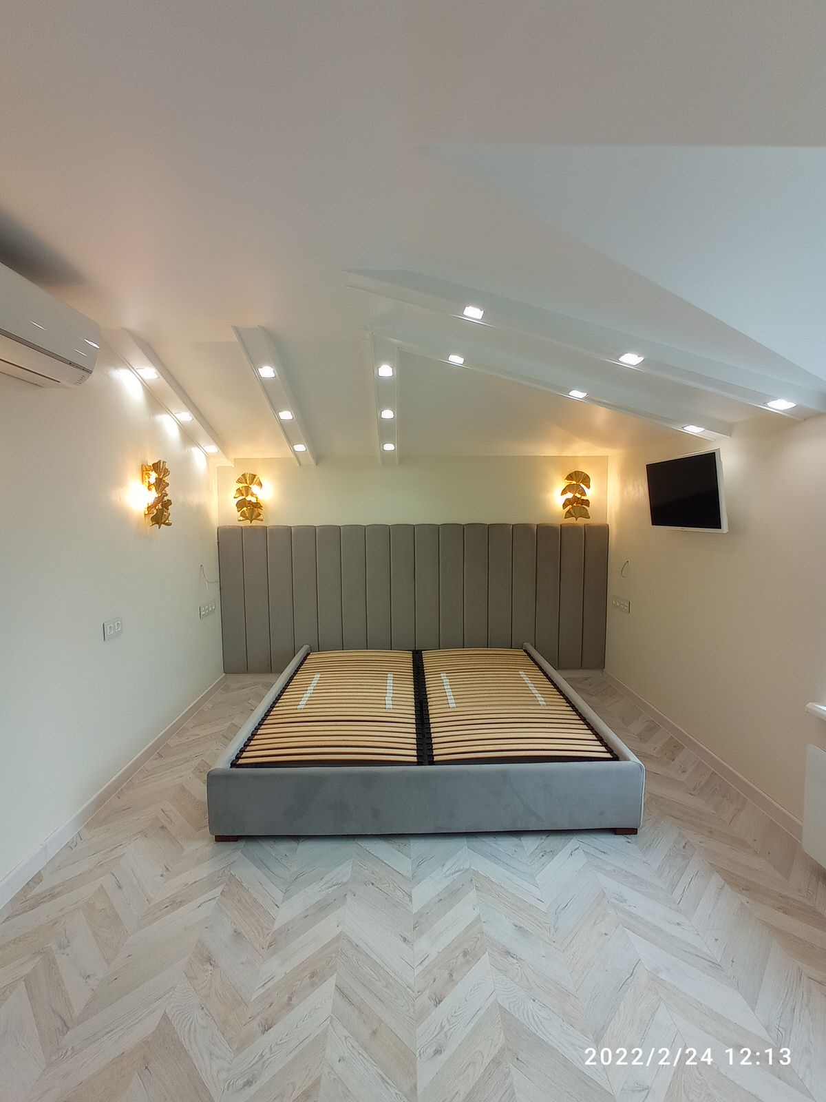 Серая кровать с панелями и золотыми бра