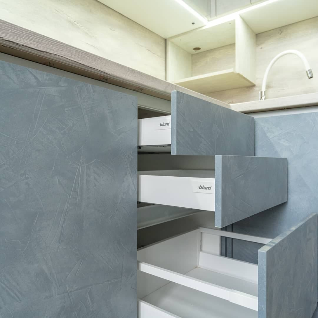 Большая угловая кухня в синем и белом цвете с фасадами под камень