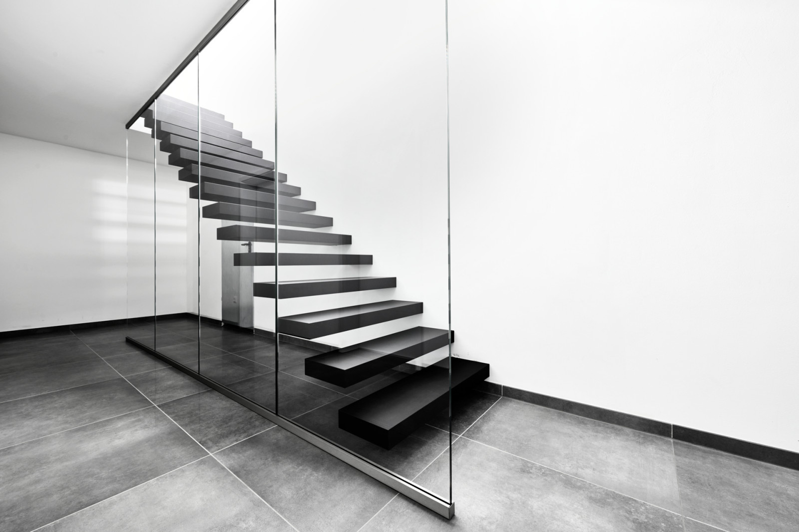 Консольная лестница в черном матовом цвете с ограждением из белого стекла