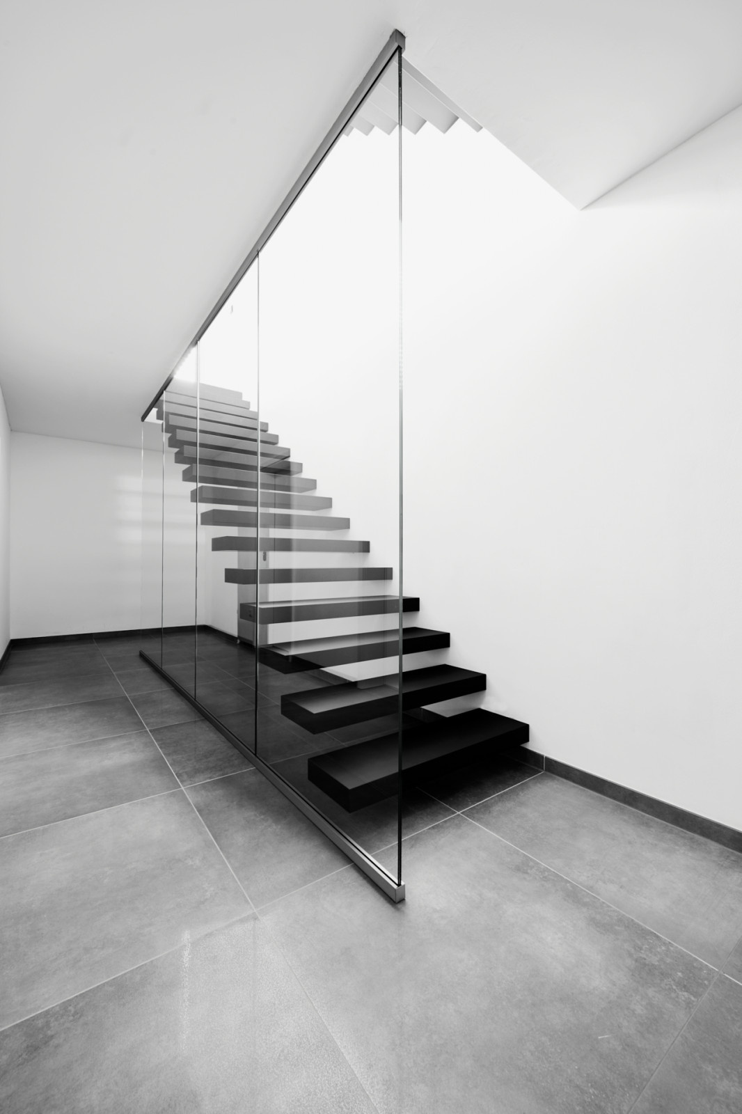 Консольная лестница в черном матовом цвете с ограждением из белого стекла