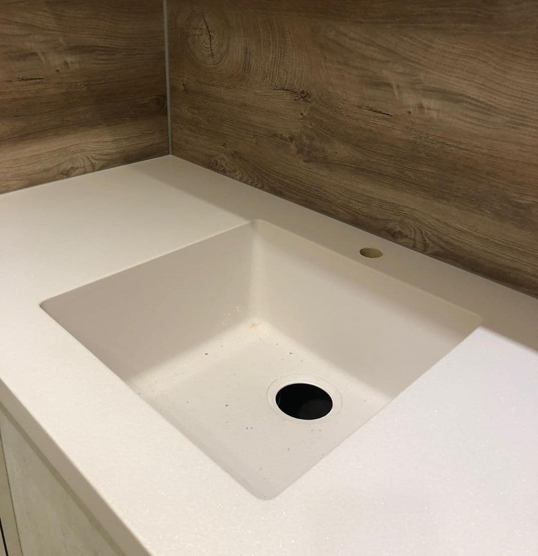 Встроенная угловая кухня с каменными и древесными фасадами