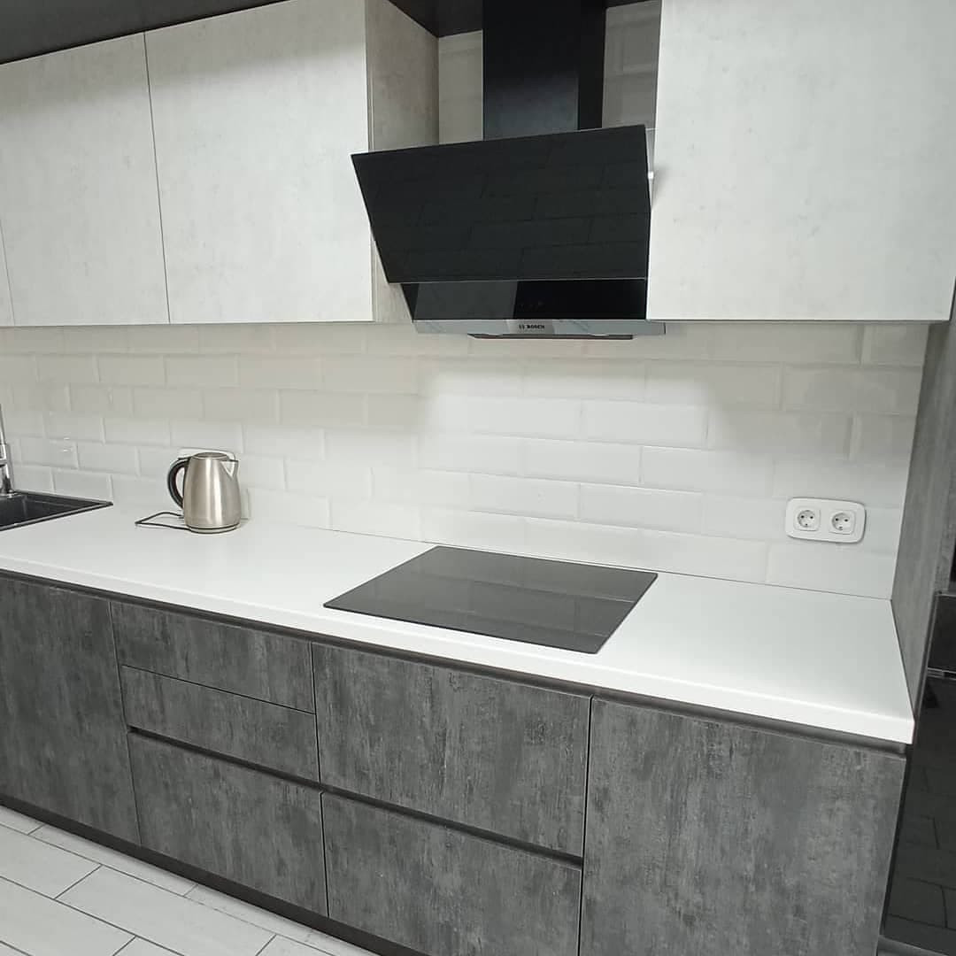 Широкая угловая черно-белая кухня с фасадами под камень