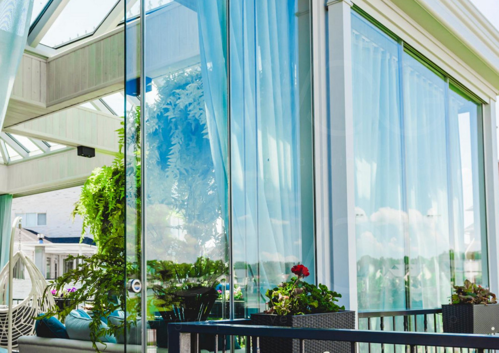 Стеклянная веранда с теплым поворотно-сдвижным и холодным безрамным остеклением