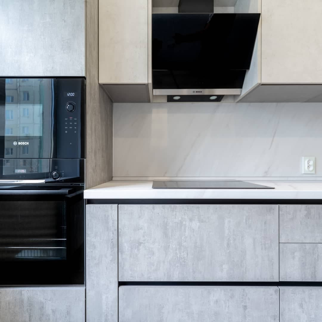 Большая светлая прямая кухня с фасадами под металл и камень