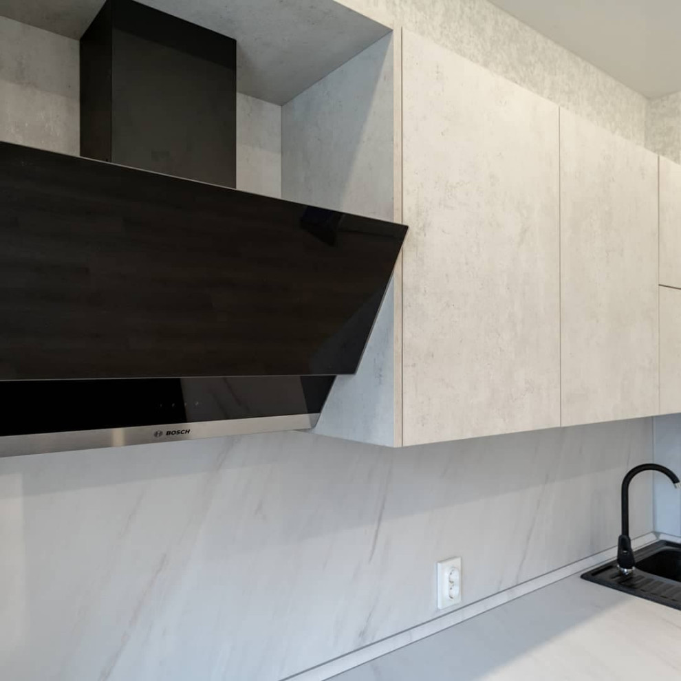 Большая светлая прямая кухня с фасадами под металл и камень