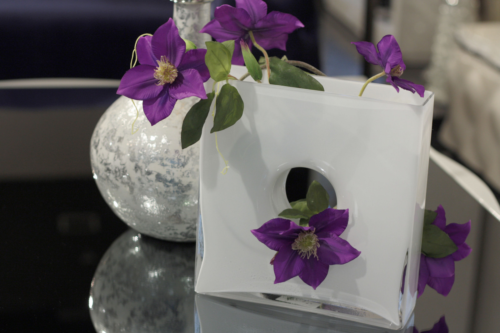 Фиолетовый цветок в белой оригинальной вазе