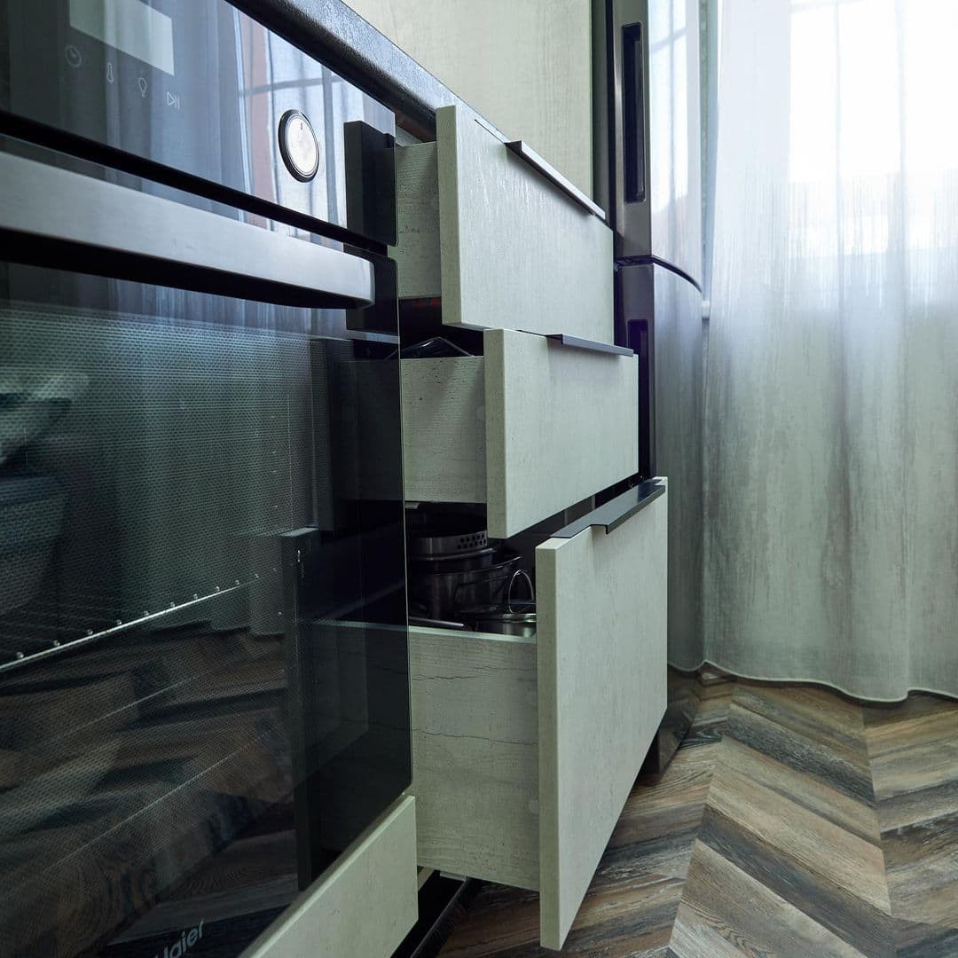 Белая угловая кухня с высокими шкафами и черной столешницей