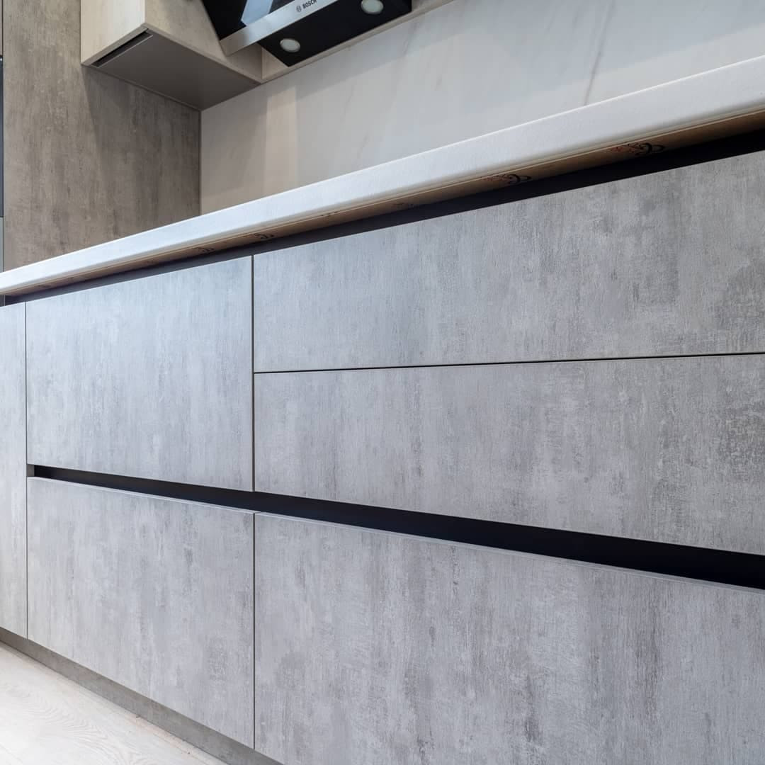 Большая светлая прямая кухня с фасадами под металл и камень