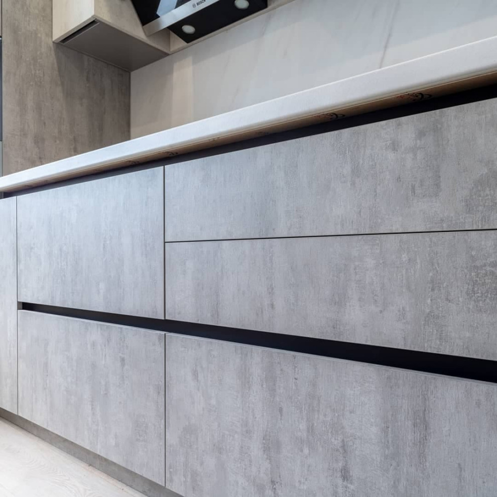 Большая светлая прямая кухня с фасадами под металл и камень