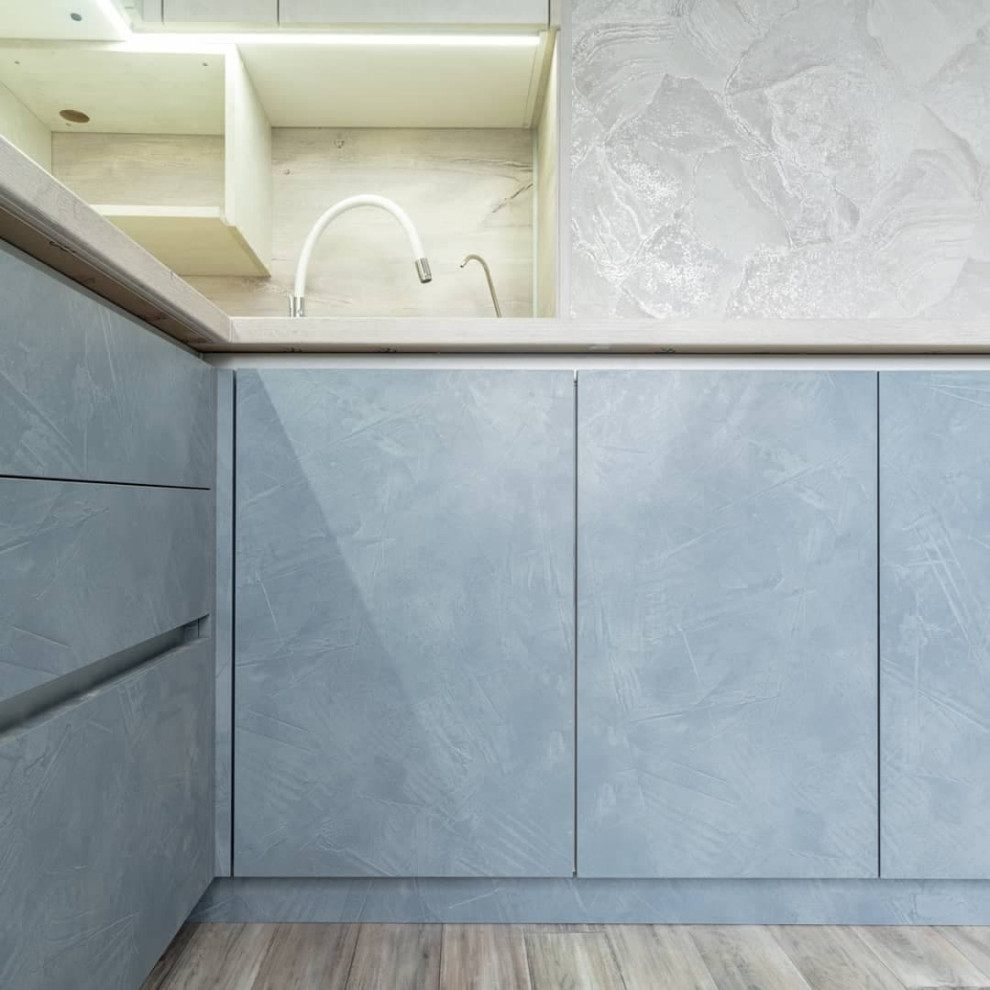 Большая угловая кухня в синем и белом цвете с фасадами под камень