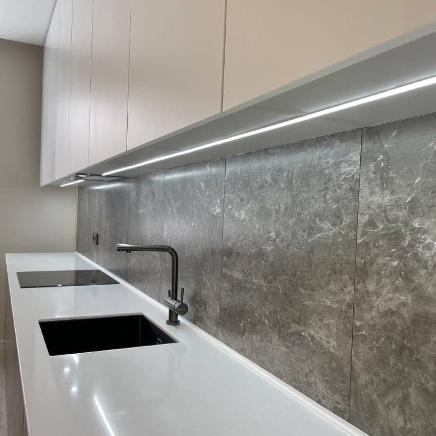 Широкая прямая кухня с высокими шкафами и фасадами под мрамор