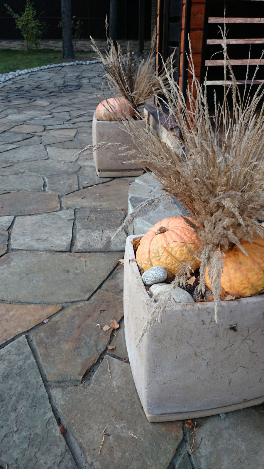 Площадка из натурального камня перед гостевым домиком с кашпо с сезонным декором