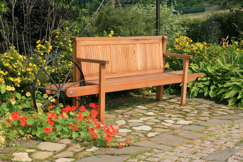 Деревянный садовый диван в окружении цветущих растений