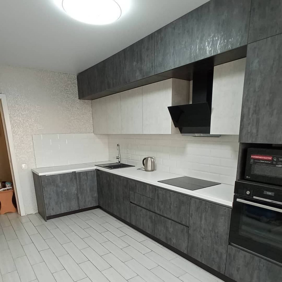 Широкая угловая черно-белая кухня с фасадами под камень