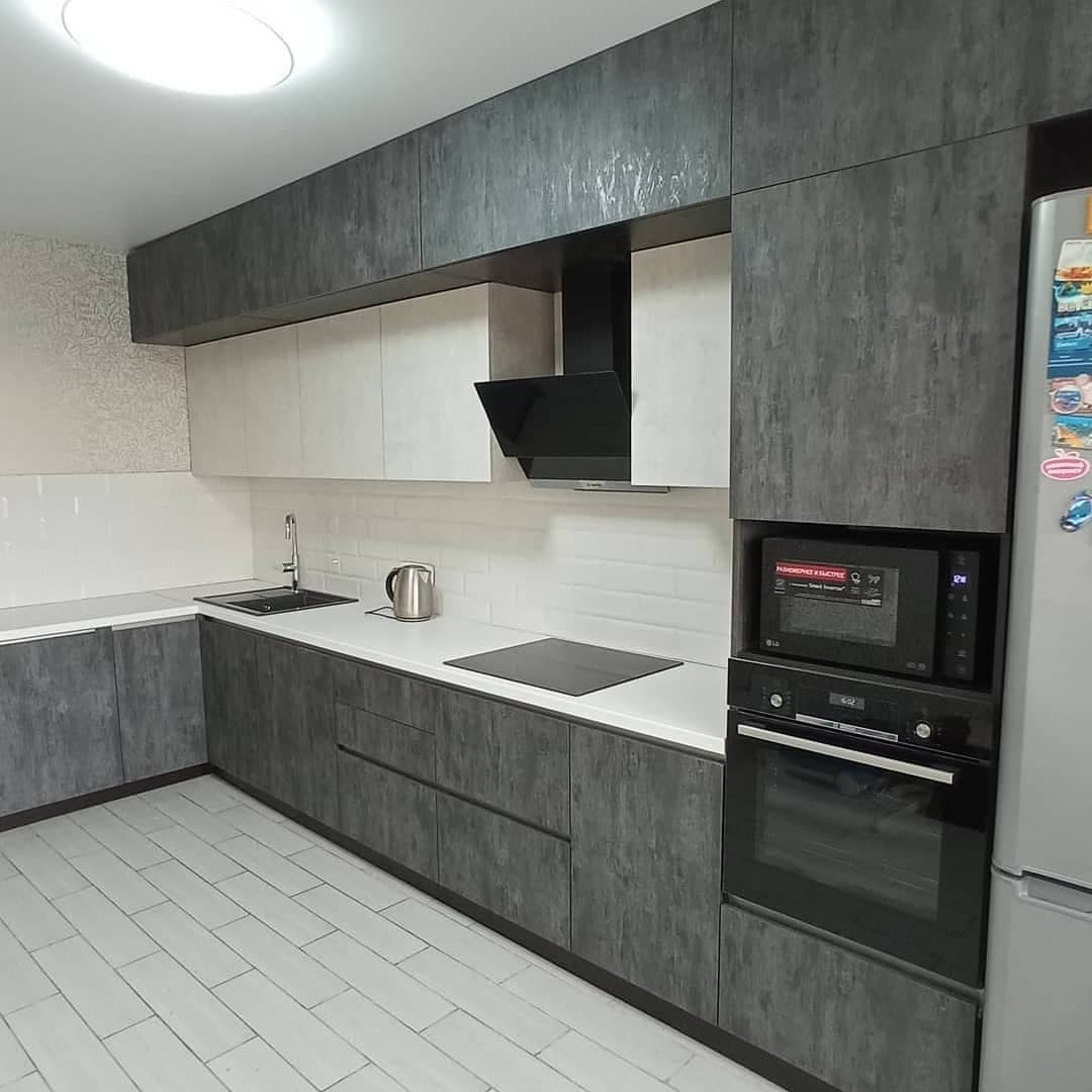 Широкая угловая черно-белая кухня с фасадами под камень