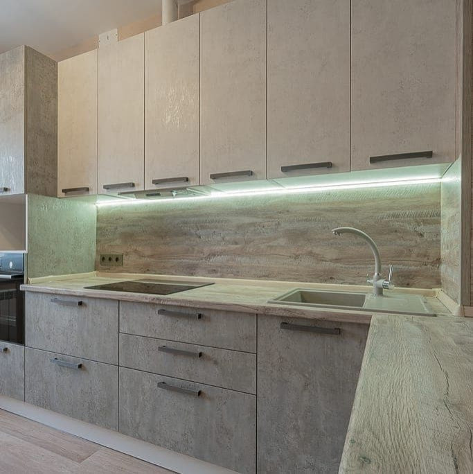 Угловая серо-белая кухня с современными ручками и фасадами под камень