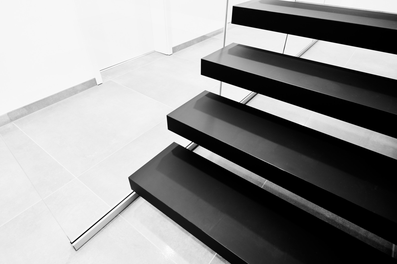 Консольная лестница в черном матовом цвете с ограждением из белого стекла