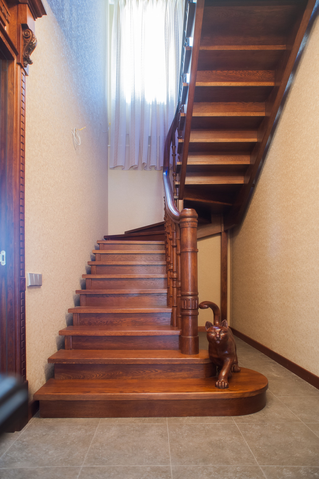 Лестница на второй этаж с забежными ступенями и деревянной фигуркой кота