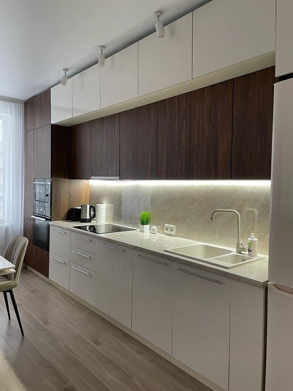 Прямая стильная кухня под потолок с глянцевыми и древесными фасадами