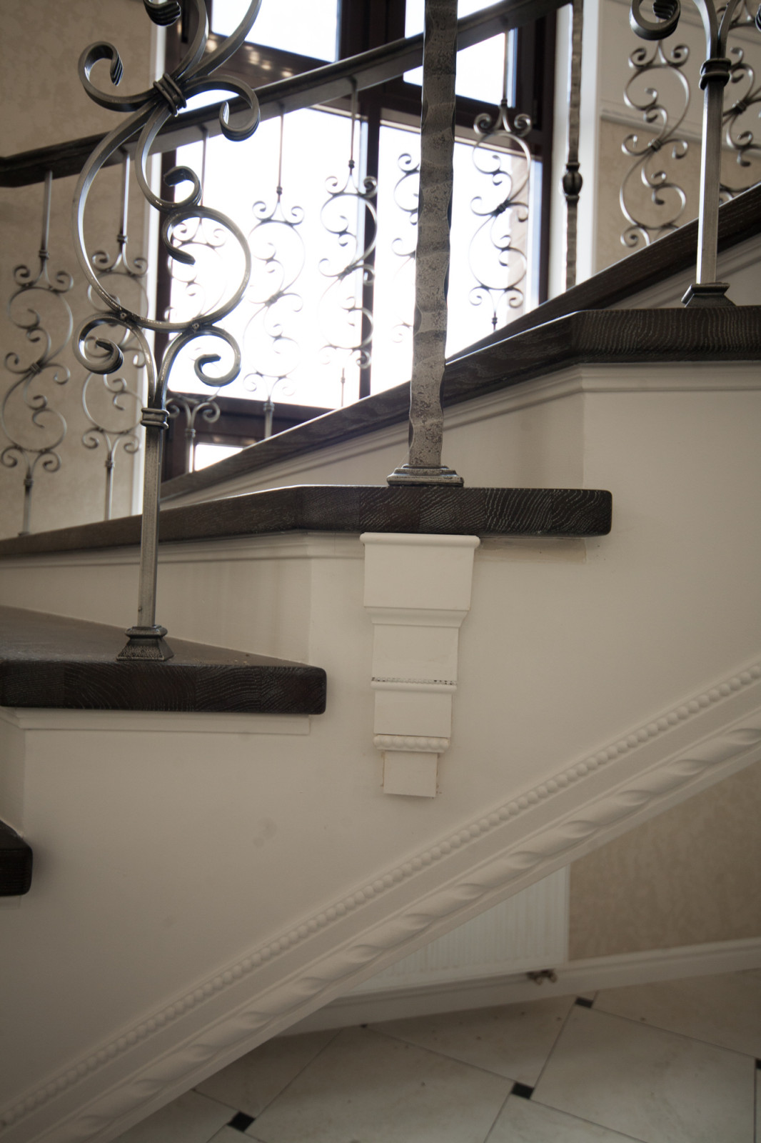 Бетонная лестница со ступенями из дуба и кованными балясинаями