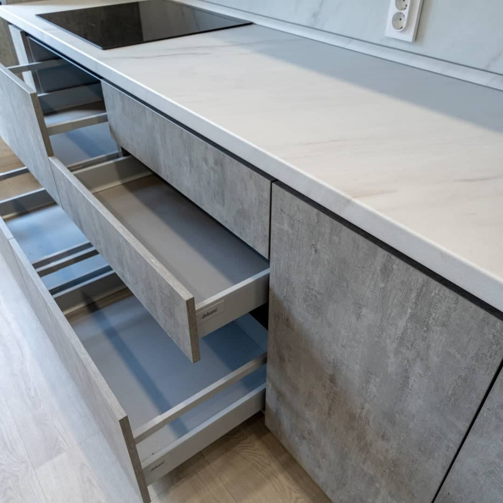 Большая светлая прямая кухня с фасадами под металл и камень