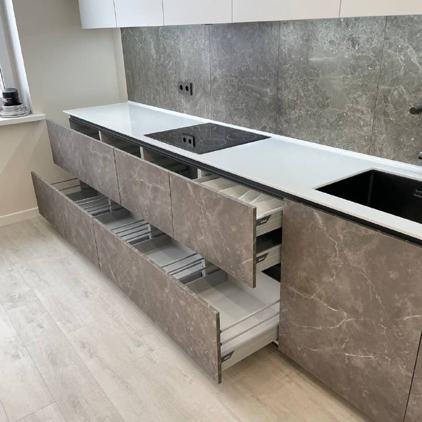 Широкая прямая кухня с высокими шкафами и фасадами под мрамор