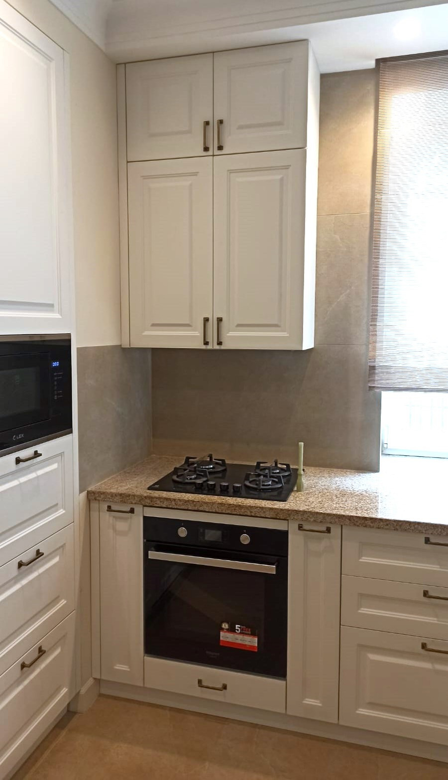 Угловая кухня в белом цвете с раковиной у окна