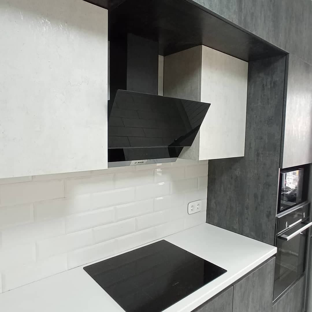 Широкая угловая черно-белая кухня с фасадами под камень
