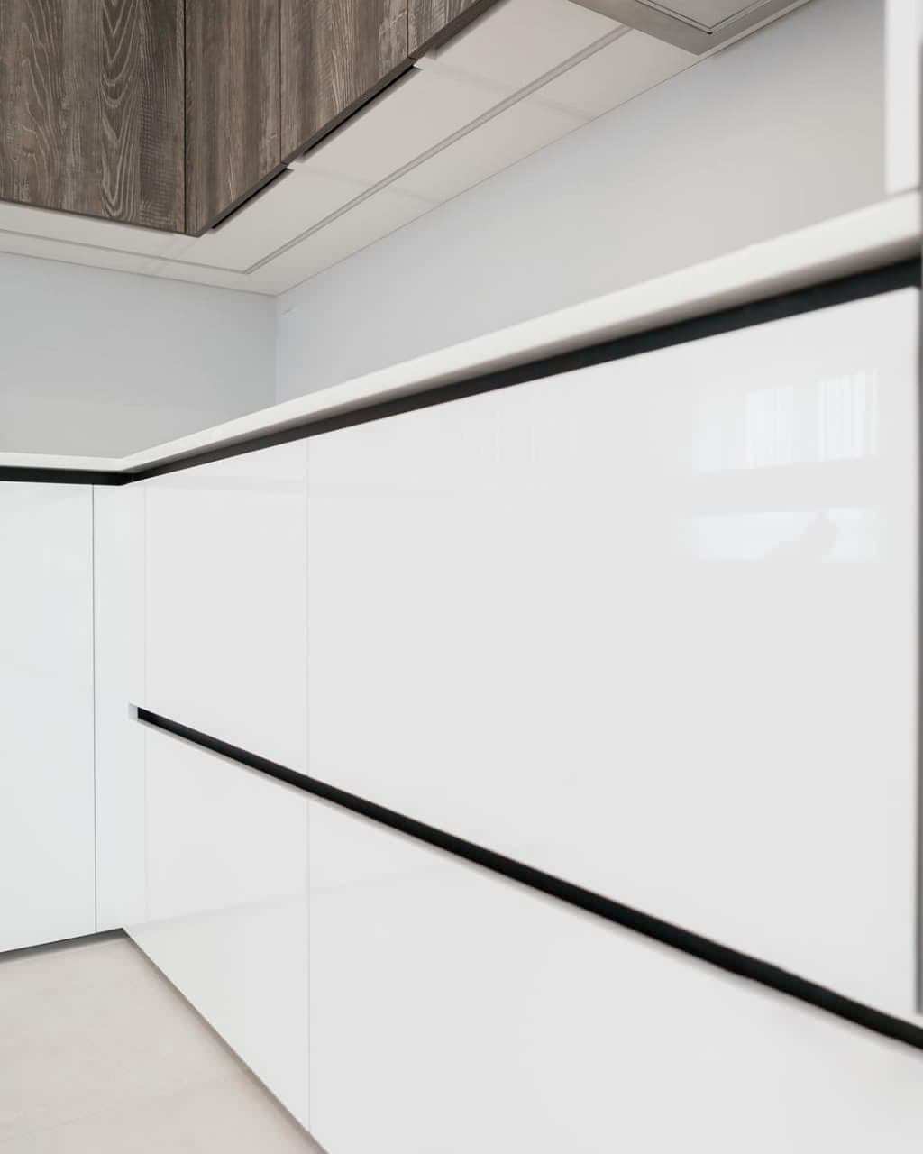 Современная серо-белая кухня в высокими шкафами и барной стойкой