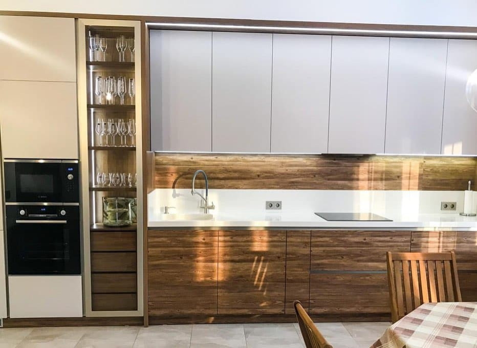 Светлая прямая кухня в стиле неоклассика со стеклянной витриной