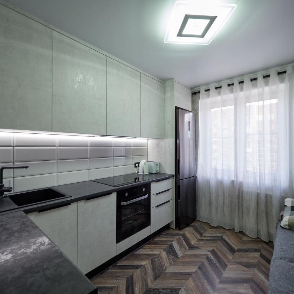 Белая угловая кухня с высокими шкафами и черной столешницей