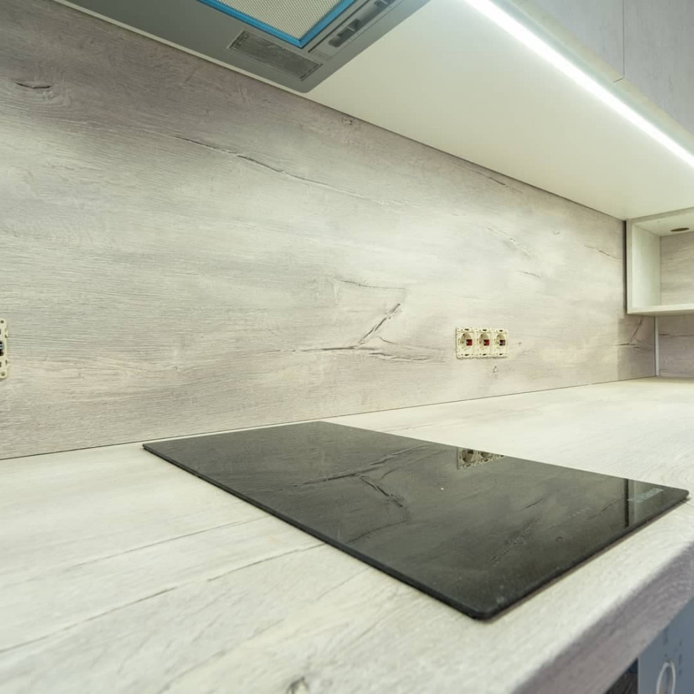 Большая угловая кухня в синем и белом цвете с фасадами под камень