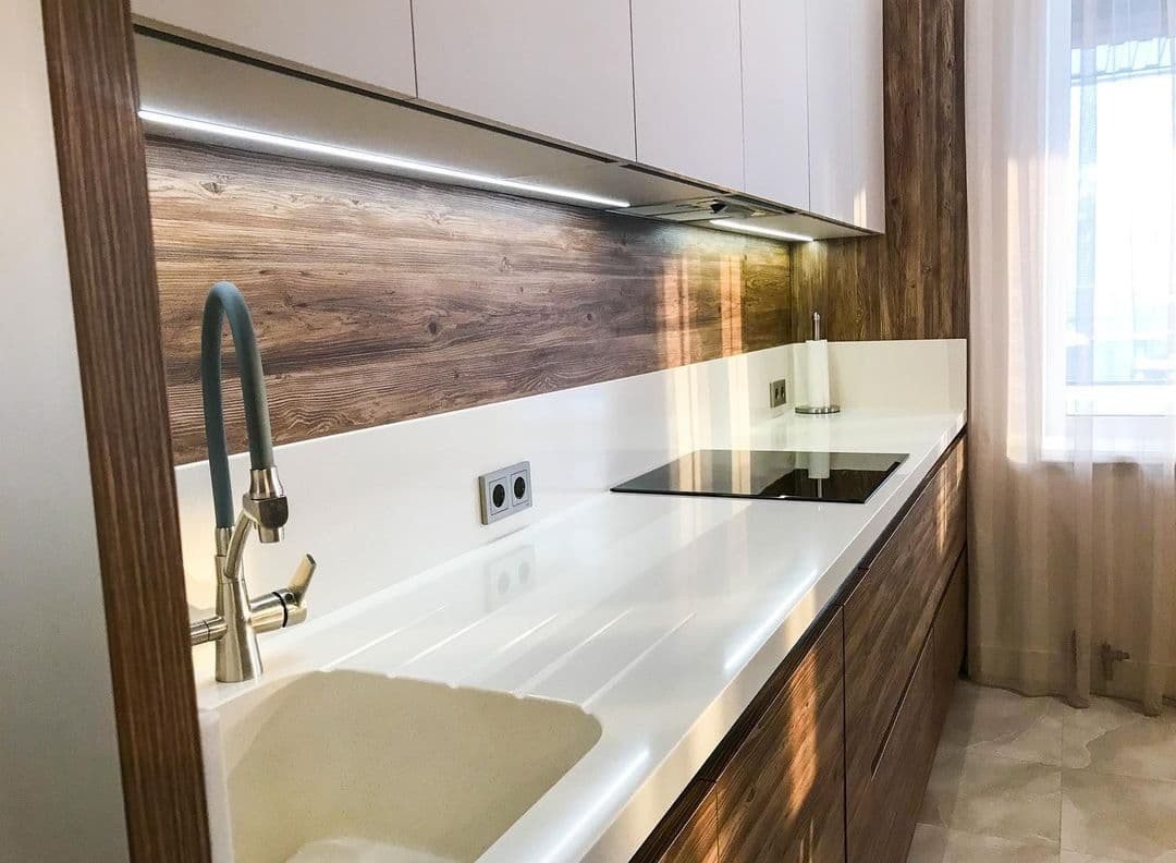 Светлая прямая кухня в стиле неоклассика со стеклянной витриной