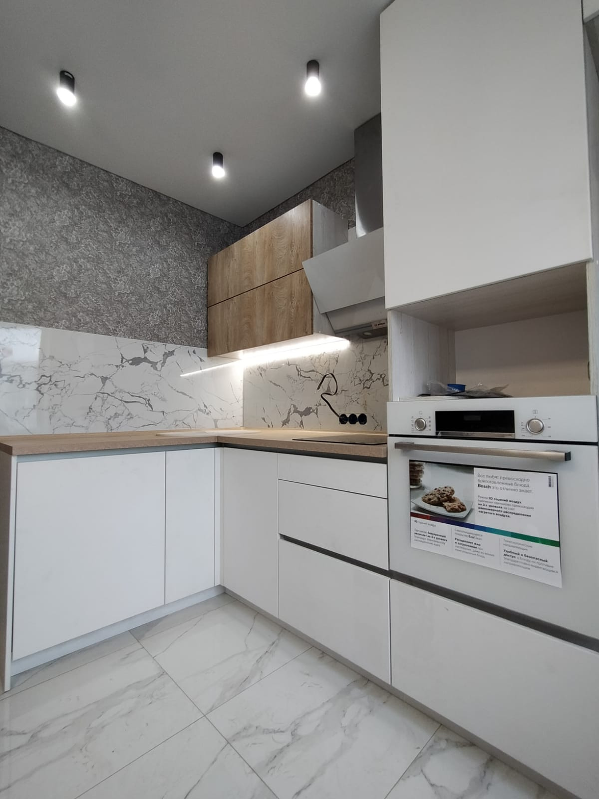 Светлая угловая белая кухня с горизонтальными верхними шкафами