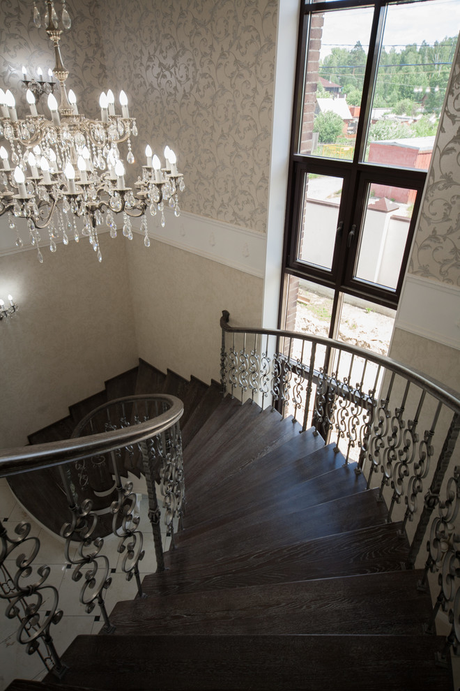 Бетонная лестница со ступенями из дуба и кованными балясинаями