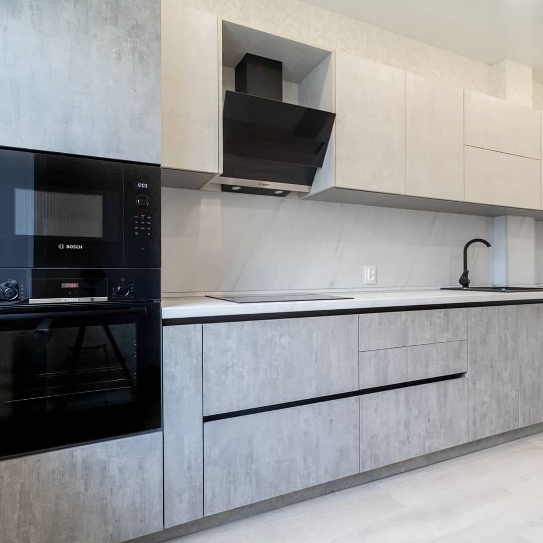 Большая светлая прямая кухня с фасадами под металл и камень