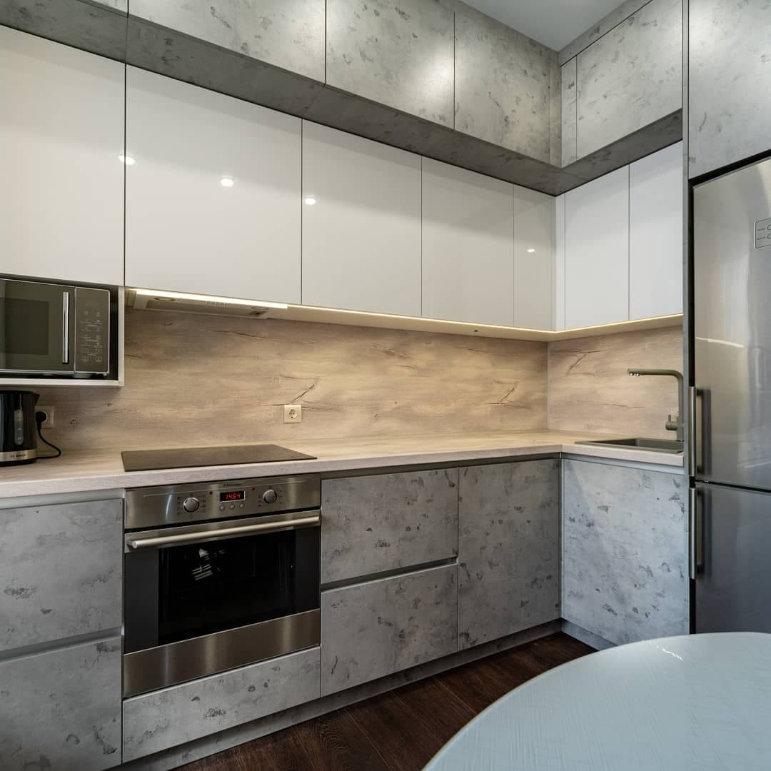 Угловая встроенная кухня с белыми глянцевыми и каменными фасадами