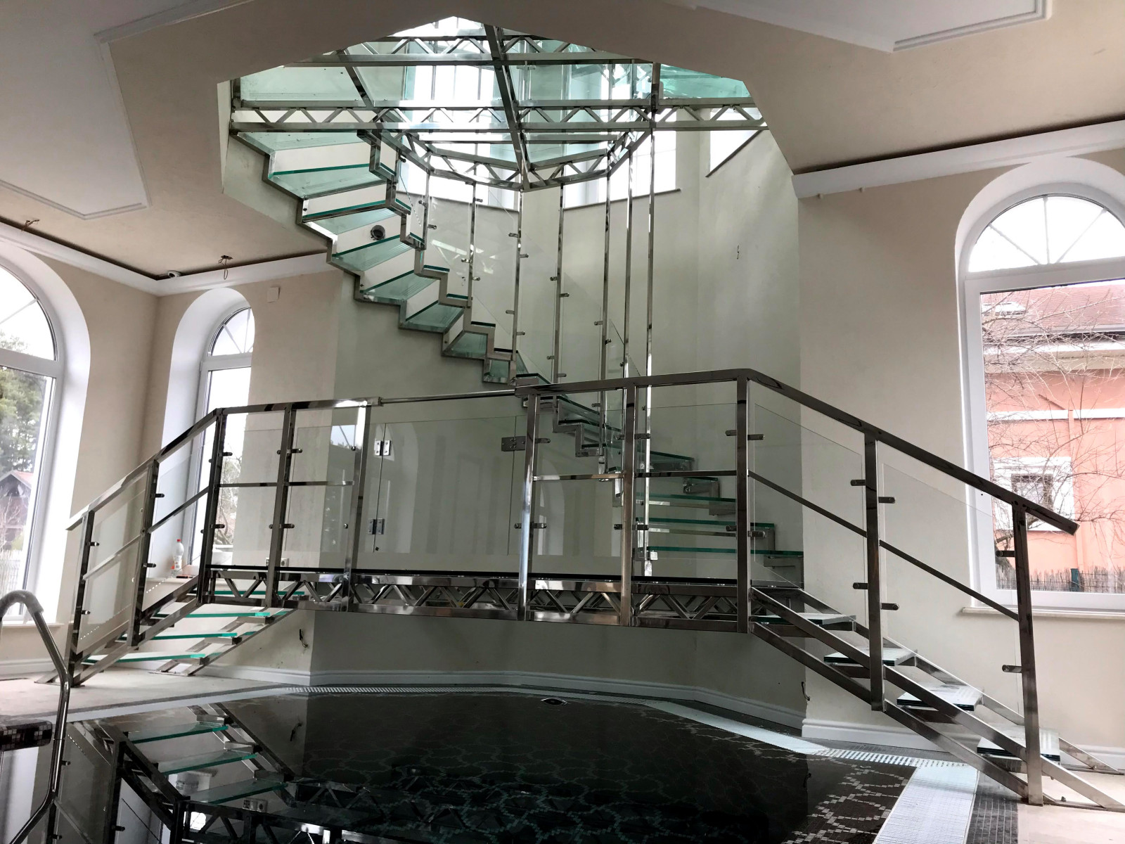 Винтовая стеклянная лестница над бассейном