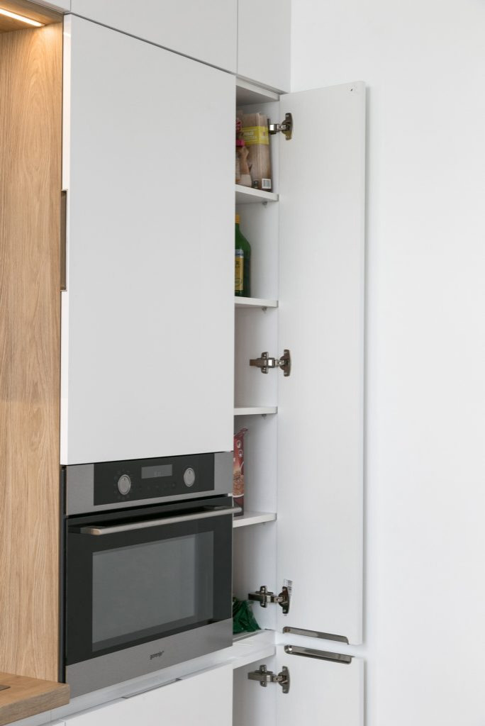 Белая глянцевая кухня с деревянными светлыми фасадами